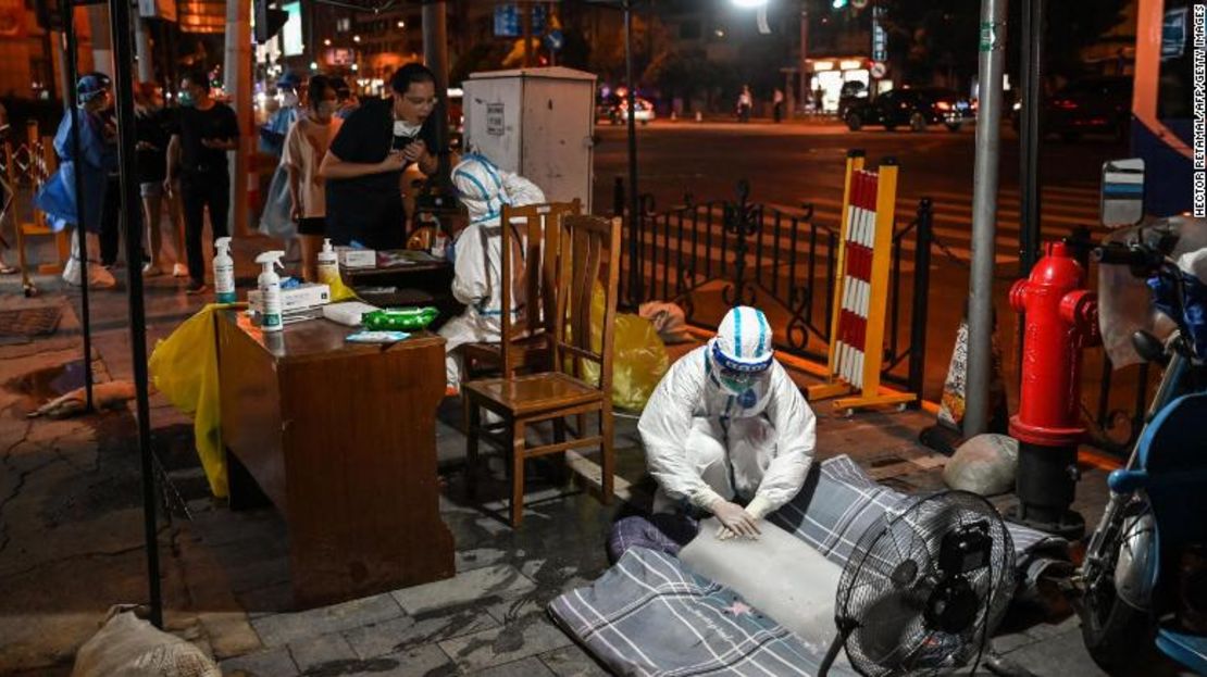 Una trabajadora sanitaria pone las manos en un bloque de hielo delante de un ventilador para refrescarse en un puesto de pruebas de Covid en Shanghai el 12 de julio.