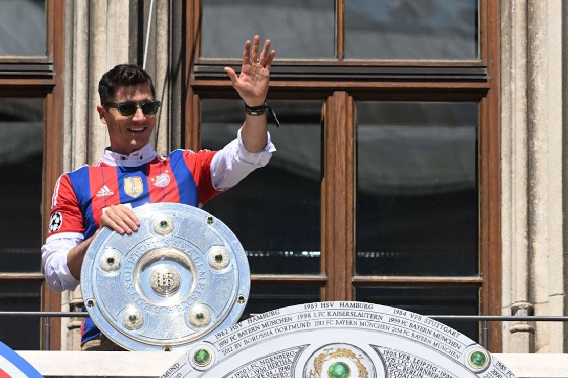 El delantero polaco del Bayern de Múnich, Robert Lewandowski, saluda desde un balcón con el trofeo de la victoria de la temporada de la Bundesliga en el centro de Múnich, el 15 de mayo de 2022, un día después del último partido de la temporada. El Bayern de Múnich se proclamó campeón de la Bundesliga por décima temporada consecutiva.