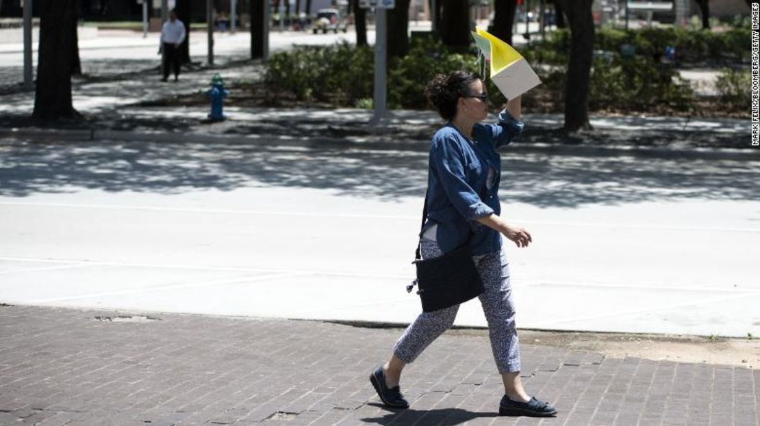 Una peatona camina con una bolsa cubriendo su cara para bloquear el sol durante la ola de calor en Houston, Texas. Crédito: Mark Felix/Bloomberg vía Getty Images