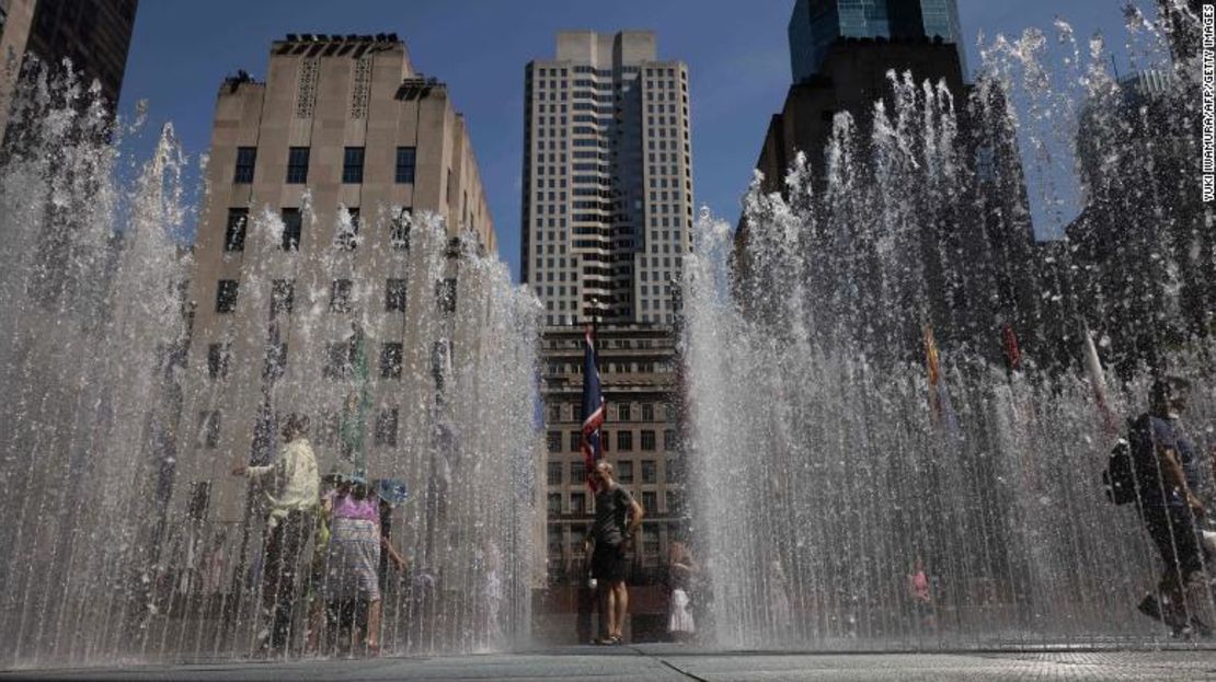 Unas personas juegan en la escultura de agua de la plaza del Rockefeller Center de Nueva York el martes.