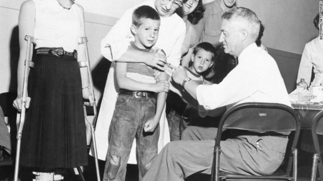 El Dr. William Burgoyne administra una inyección de la vacuna contra la polio de Salk a Michael Urnezis, de 6 años, mientras la hermana del niño, Joanne, de 12 años, paciente de polio, observa en 1955 en San Diego.