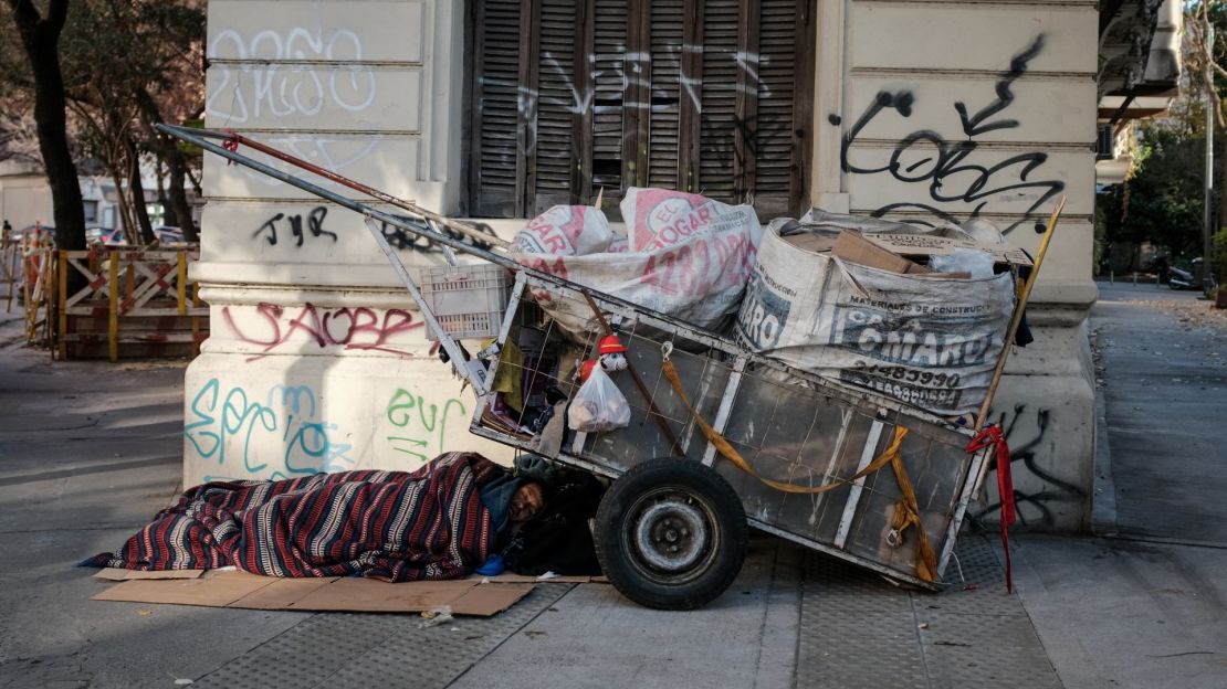 Una persona sin hogar duerme en la calle junto a su carro de recogida de cartón el 10 de junio de 2022 en Buenos Aires, Argentina.