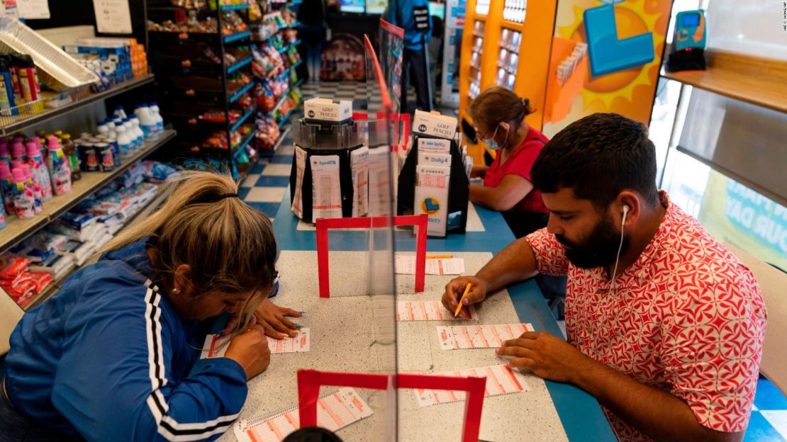 Nancy Linares, a la izquierda, y Prince Joseph Israel llenan boletos de Mega Millions en Blue Bird Liquor en Hawthorne, California, el martes.