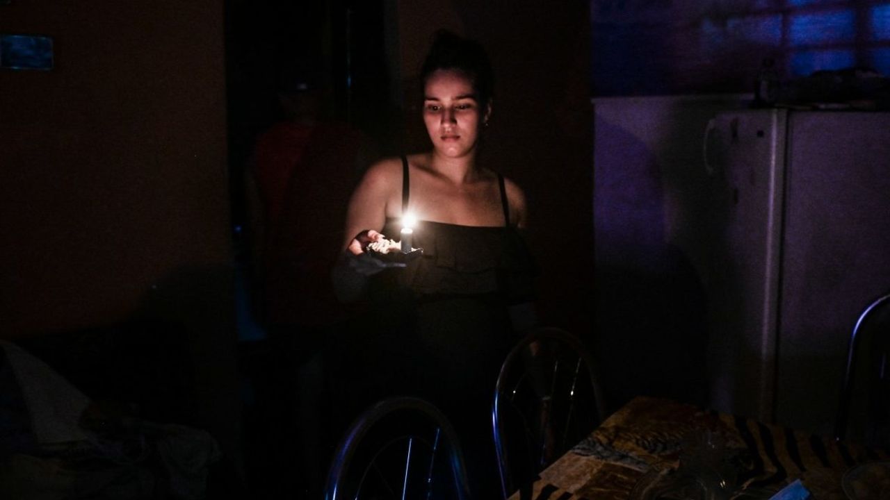 Una mujer sostiene una vela durante un apagón en La Habana, el 25 de mayo de 2022.- La principal central termoeléctrica de Cuba fue alcanzada este martes por un rayo que la dejó fuera de servicio, pues la isla sufre constantes apagones por fallas y trabajos de mantenimiento en varias de sus plantas de generación de energía, informó la presidencia.