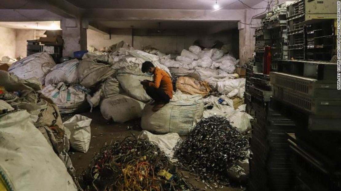 Un hombre se sienta frente a desechos electrónicos de computadoras en un taller en Nueva Delhi, India, en julio de 2020.