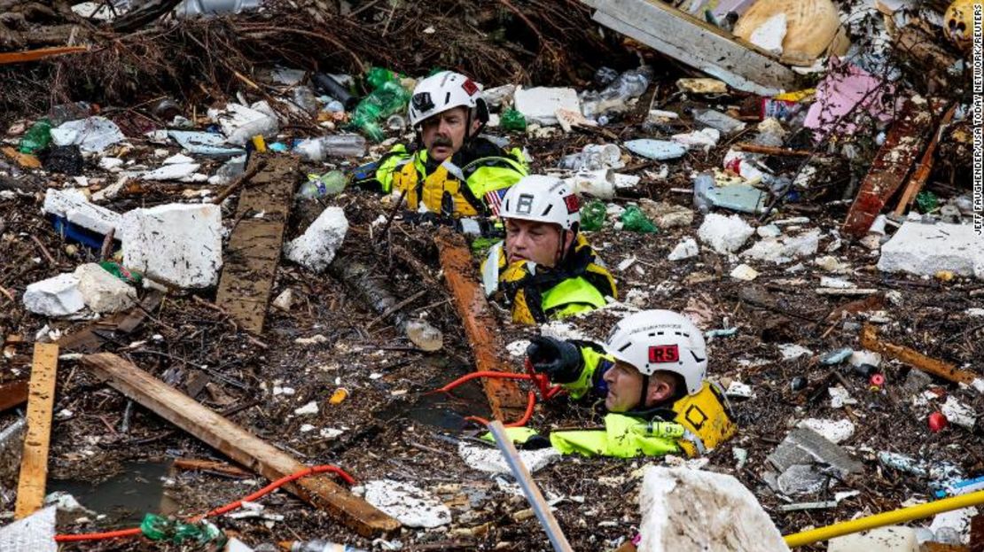 Miembros del equipo de búsqueda y rescate Tennessee Task Force One atraviesan el arroyo Troublesome, lleno de escombros, después de que un perro de búsqueda detectara el domingo el olor de una posible víctima de las inundaciones.