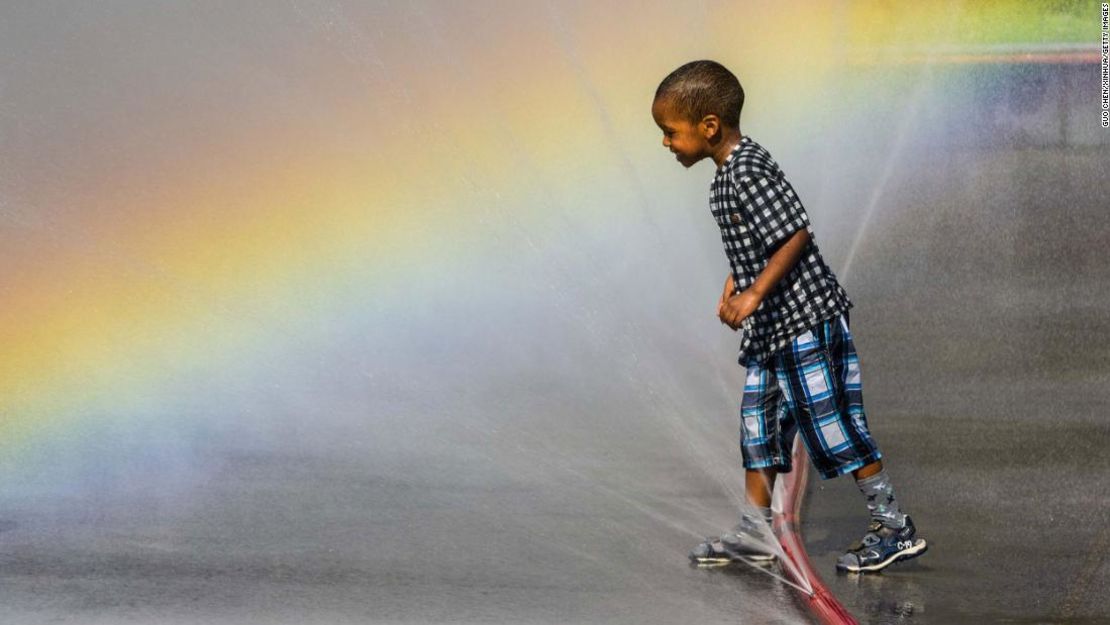 Un niño utiliza una fuente de agua para refrescarse en la plaza Schwarzenberg de Viena, Austria.