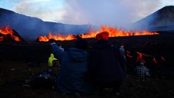 People look at the lava erupting and flowing at the scene of the newly erupted volcano at Grindavik, Iceland on August 3, 2022. - A volcano erupted on August 3, 2022 in Iceland in a fissure near Reykjavik, the Icelandic Meteorological Office (IMO) said as lava could be seen spewing out of the ground in live images on local media. The eruption was some 40 kilometres (25 miles) from Reykjavik, near the site of the Mount Fagradalsfjall volcano that erupted for six months in March-September 2021, mesmerising tourists and spectators who flocked to the scene. (Photo by Jeremie RICHARD / AFP)