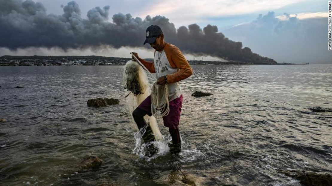 Un hombre pesca mientras sale humo del enorme incendio en un depósito de combustible en Matanzas, Cuba, el 9 de agosto de 2022.