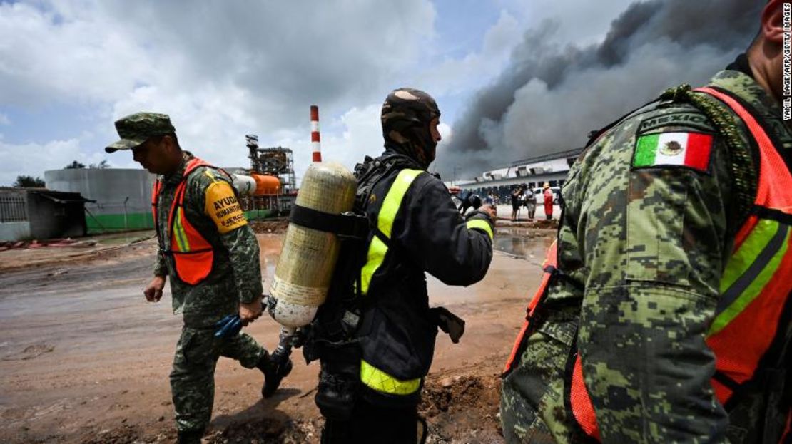 Bomberos mexicanos y cubanos trabajan para apagar el incendio en el depósito de combustible que fue provocado por la caída de un rayo.