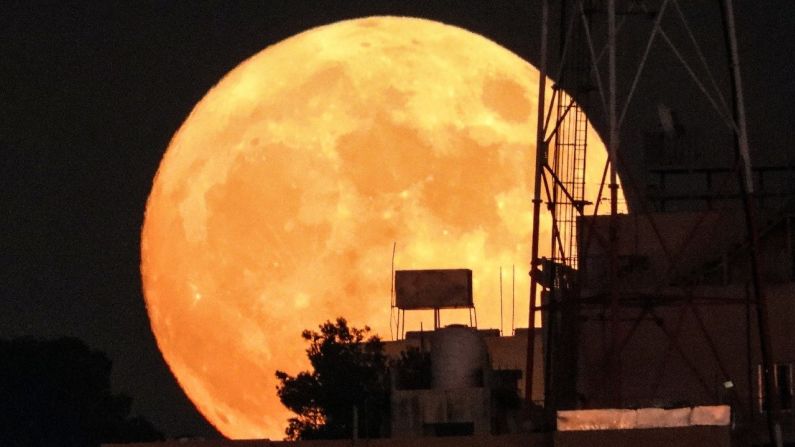 La luna llena de esturión se eleva sobre los edificios en la capital de Jordania, Amman, el 11 de agosto de 2022.