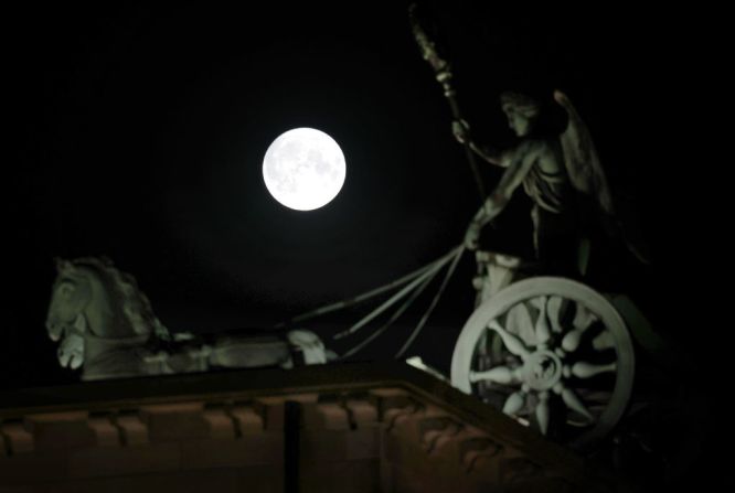 La luna llena de esturión se eleva detrás de la estatua de Quadriga en la Puerta de Brandenburgo el 11 de agosto de 2022 en Berlín, Alemania.