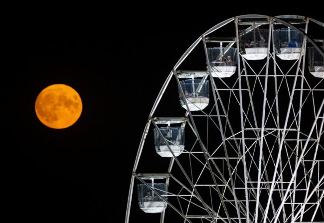 La luna llena de agosto conocida como luna de esturión se eleva detrás de la noria en Bristol International Balloon Fiesta en Ashton Court Estate, el 11 de agosto de 2022 en Bristol, Inglaterra.