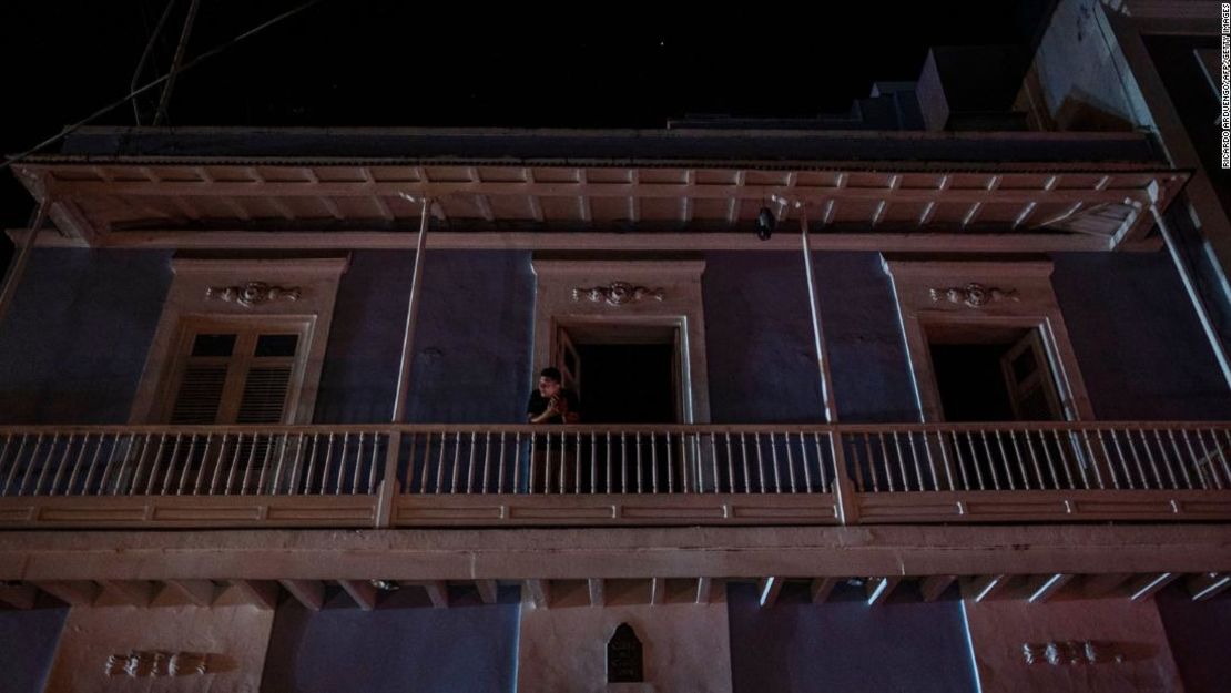 Un hombre se para en un balcón en San Juan después de un gran corte de energía el 6 de abril de 2022.