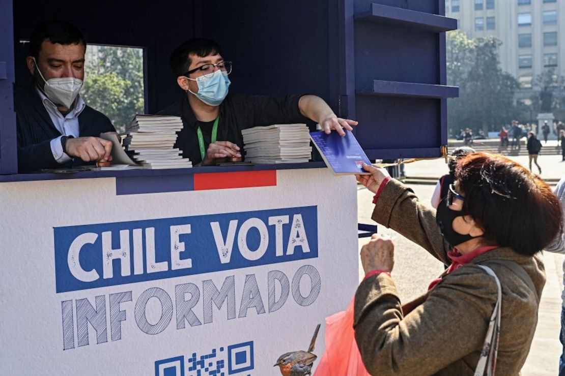 Una mujer recibe una copia del borrador de la nueva constitución de Chile frente al palacio presidencial de La Moneda en Santiago, el 11 de agosto de 2022. - Chile vota el 4 de septiembre en un plebiscito si aprueba o rechaza el borrador de la nueva constitución.