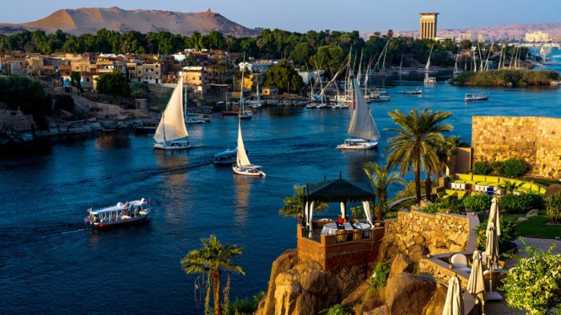 Egipto: los veleros se deslizan por las aguas del río más largo del mundo, el Nilo, en Asuán. Este es un lugar estupendo para "tomarse unas vacaciones de sus vacaciones" en Egipto. Reserva un hotel con una vista como ésta y déjate envolver por el paisaje y el ambiente. Crédito: spiritofamerica/Adobe Stock