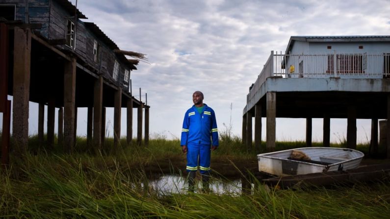 Jasper Doest tomó un retrato de Lubinda Lubinda, director de la estación de la Autoridad del Río Zambeze, que revela el impacto de la sequía en la llanura de inundación. La fauna depende de las inundaciones regulares, al igual que el pueblo barotse. La bajada del nivel del agua hace que la nueva casa de Lubinda (a la derecha) no tenga que ser tan alta. Crédito: Jasper Doest/Fotógrafo de Vida Silvestre de 2022