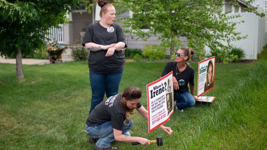 Lacey Ayers habla con Stacy Koester, izquierda, y Melissa Bloxom mientras colocan carteles con una imagen de Irene Gakwa en un patio en Gillette, Wyoming. Gakwa vivía con su novio en la casa de al lado.