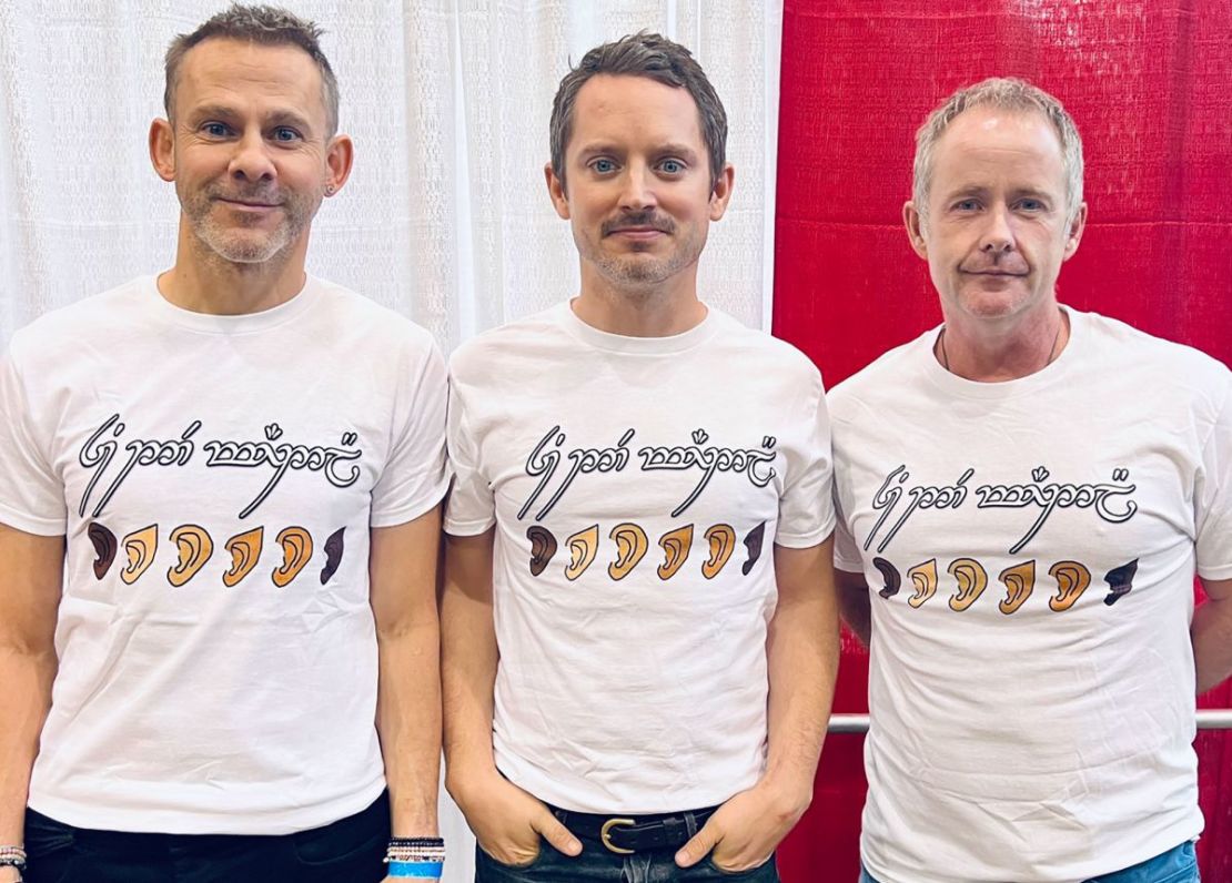 Elijah Wood (centro), Dominic Monaghan (izquierda) y Billy Boyd (derecha) usaron camisetas que decían "Todos ustedes son bienvenidos aquí" en élfico para apoyar a los actores de "El señor de los anillos: Los anillos del poder", varios de los cuales han sido objeto de comentarios racistas.