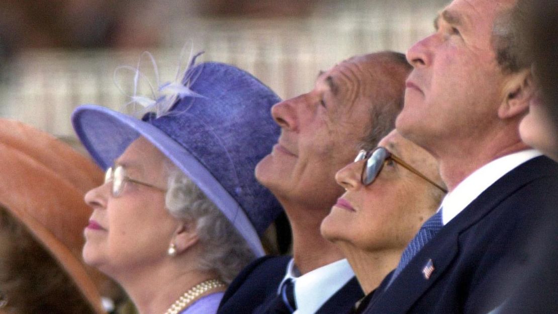 George W. Bush: visitó Gran Bretaña en una visita oficial de Estado en 2003, y la reina fue a Estados Unidos en 2007 para celebrar el 400º aniversario de la fundación de Jamestown. Durante su discurso de bienvenida, Bush dijo: "Usted ayudó a nuestra nación a celebrar su bicentenario en 17...". Al darse cuenta de su error al sugerir que la reina, que entonces tenía 81 años, llevaba en el trono desde el siglo XVIII, Bush se volvió hacia la monarca y le guiñó un ojo. Más tarde Bush dijo que ella le dirigió "una mirada que solo una madre puede dirigir a un hijo". Aquí se les ve en junio de 2004 viendo un sobrevuelo en Arromanches, Francia. Era el 60º aniversario del desembarco del Día D.