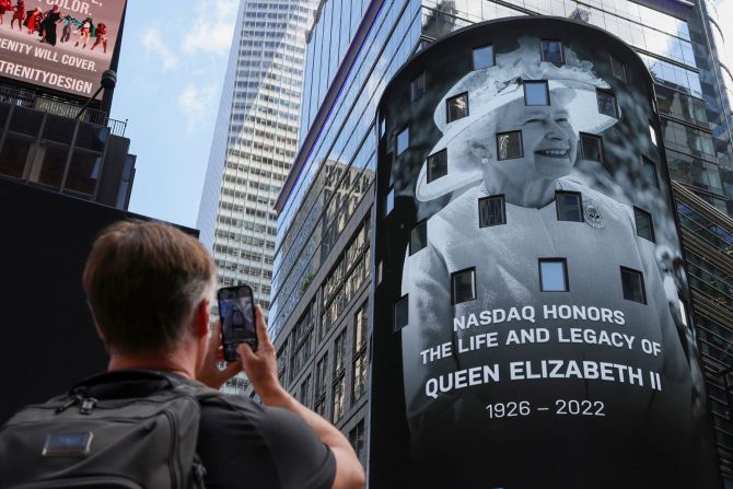 Una persona toma una foto mientras aparece un tributo a la reina Isabel II en la pantalla de la valla publicitaria Nasdaq MarketSite en Times Square, Nueva York. Andrew Kelly/Reuters