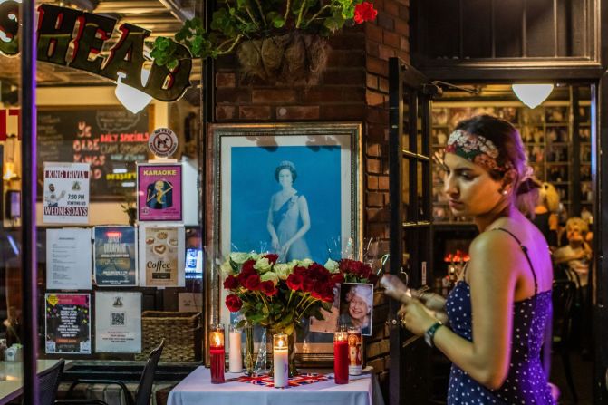 Una mujer pasa frente a un monumento improvisado en memoria de la difunta reina Isabel II frente a un pub británico en Santa Mónica, California. Apu Gomes/AFP/Getty Images