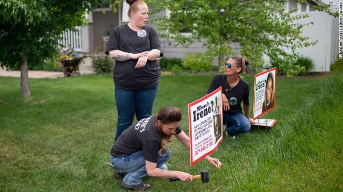 Lacey Ayers habla con Stacy Koester, izquierda, y Melissa Bloxom mientras colocan carteles con una imagen de Irene Gakwa en un patio en Gillette, Wyoming.