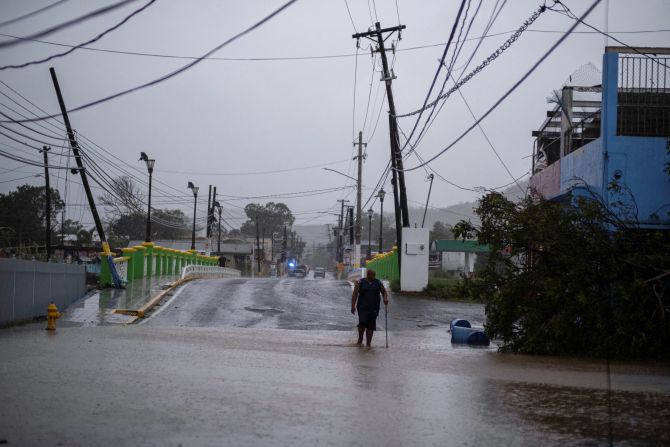 Un hombre camina por una calle inundada en Yauco, Puerto Rico, el domingo.