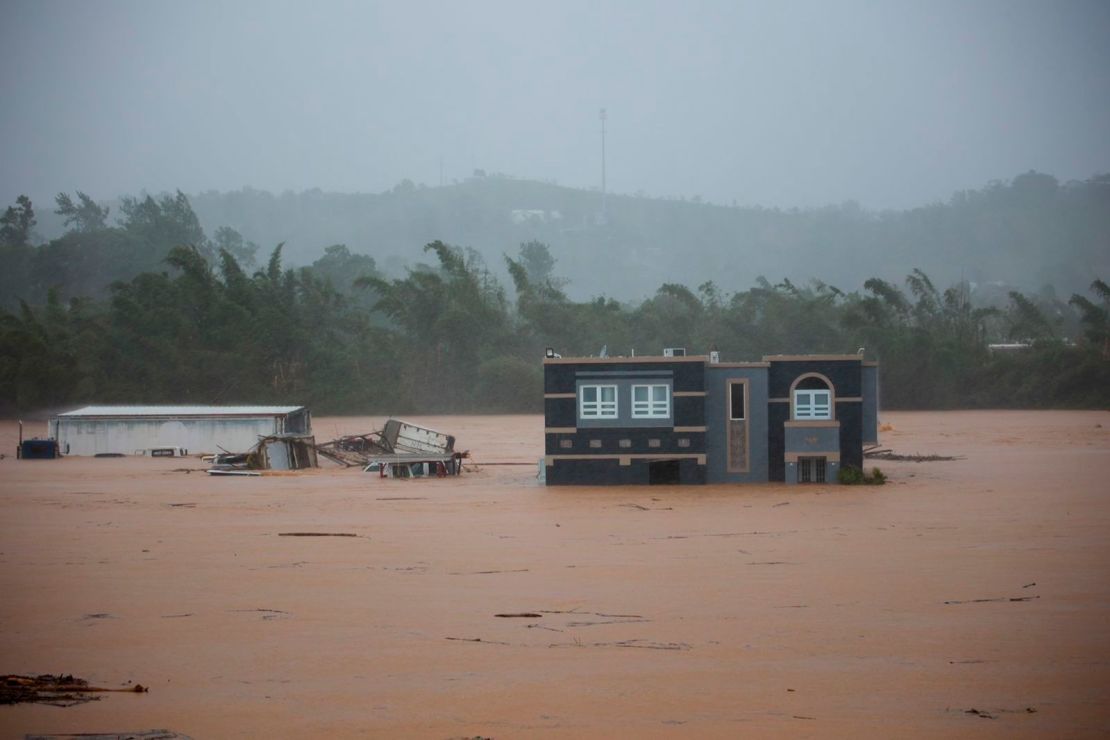 Tres personas dentro de una casa esperan que las rescaten de las inundaciones causadas por el huracán Fiona en Cayey, Puerto Rico. Crédito: Stephanie Rojas/AP