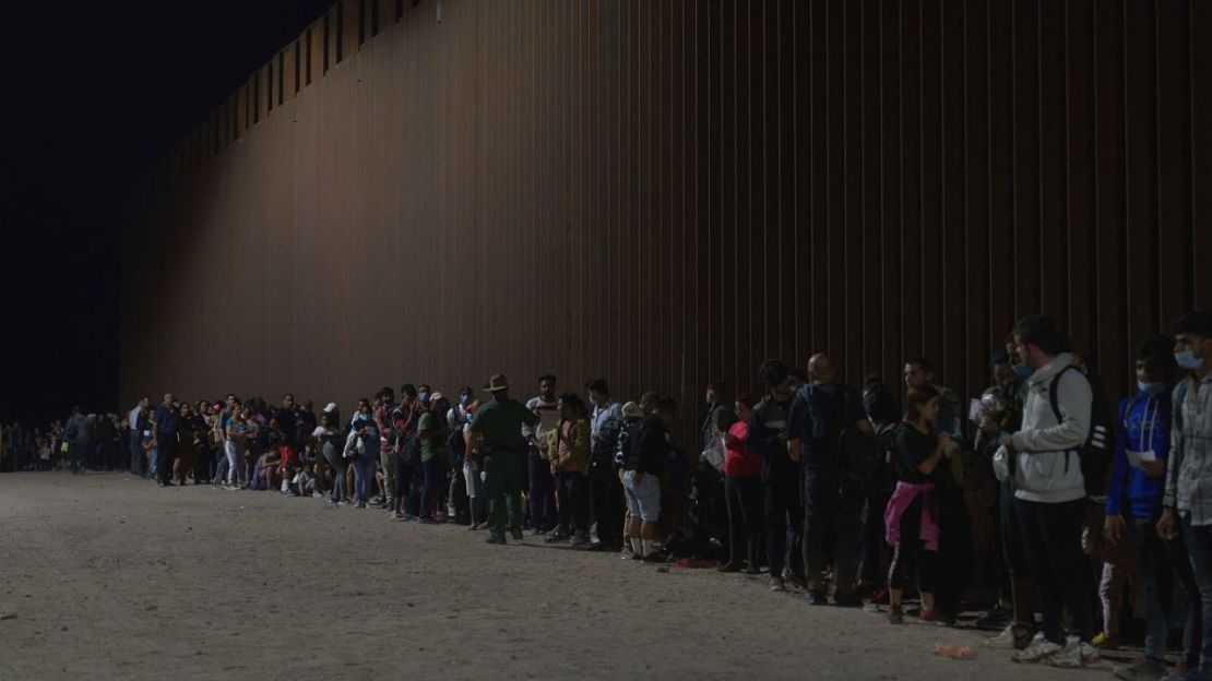 Migrantes hacen fila mientras esperan ser procesados por la Patrulla Fronteriza de EE. UU. después de cruzar ilegalmente la frontera entre EE. UU. y México en Yuma, Arizona, en la madrugada del 11 de julio de 2022.