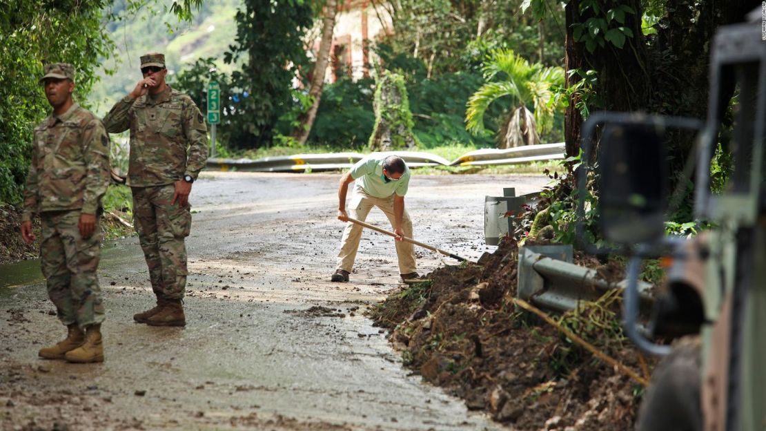 La Guardia Nacional dirige el tráfico en Cayey, Puerto Rico, mientras el residente Luis Noguera ayuda a despejar el camino.