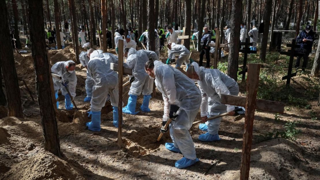 Miembros del Servicio de Emergencia de Ucrania trabajan en una fosa común durante una exhumación en la ciudad recientemente liberada de Izium, en la región de Járkiv en Ucrania el 19 de septiembre de 2022.