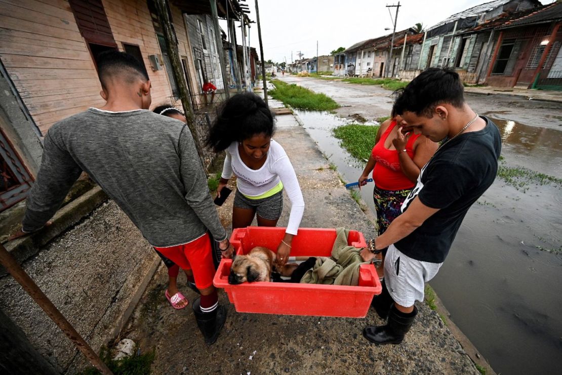 Una familia lleva a un perro a un lugar seguro en Batabanó, Cuba, el lunes. Crédito: Adalberto Roque/AFP/Getty Images