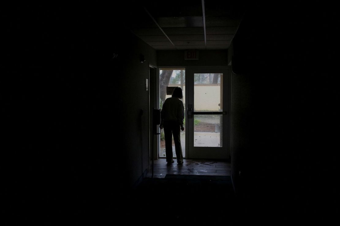 Una mujer observa los daños a través de una puerta durante un corte de electricidad en Fort Myers, el miércoles. Crédito: Marco Bello/Reuters