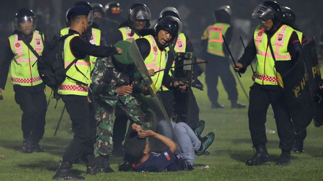 Agentes de seguridad detienen a un aficionado durante un enfrentamiento entre simpatizantes de dos equipos de fútbol de Indonesia en el estadio Kanjuruhan en Malang, Java Oriental, Indonesia.