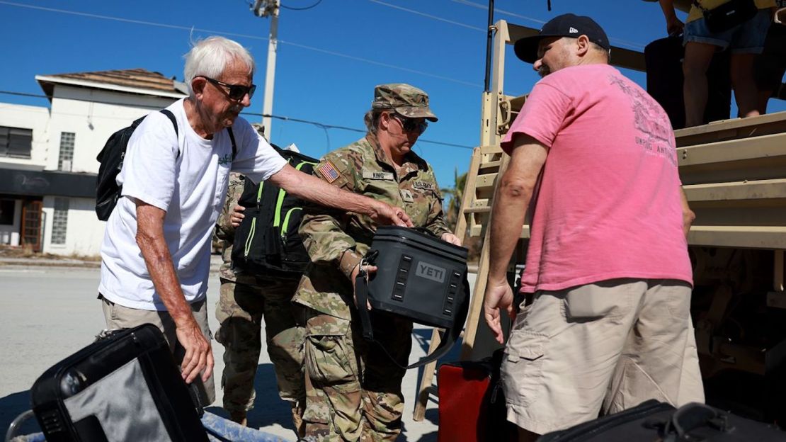 Miembros de la Guardia Nacional del Ejército de Florida ayudan a Tim Tuitt (L) y John Davis mientras son evacuados de Fort Myers Beach el lunes tras el paso del huracán Ian.