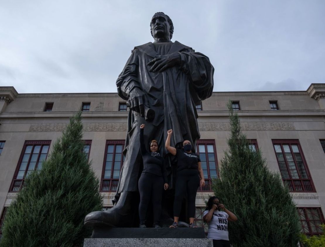 Los manifestantes levantan los puños en la base de una estatua de Cristóbal Colón frente al Ayuntamiento durante una protesta de Black Lives Matters contra la brutalidad policial en el centro de Columbus, Ohio, el 27 de junio de 2020