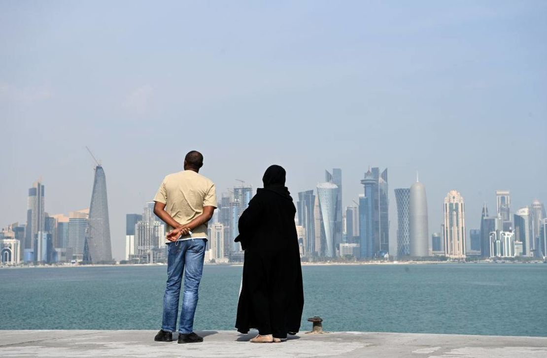 Dos personas contemplan los rascacielos sobre la costa de Doha, Qatar.