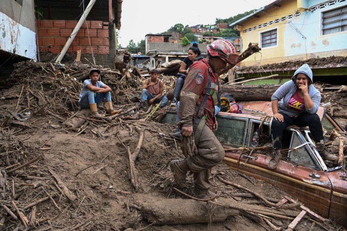 Los residentes permanecen encima de un vehículo semienterrado mientras los rescatistas buscan a sus familiares desaparecidos. Crédito: YURI CORTEZ/AFP vía Getty Images