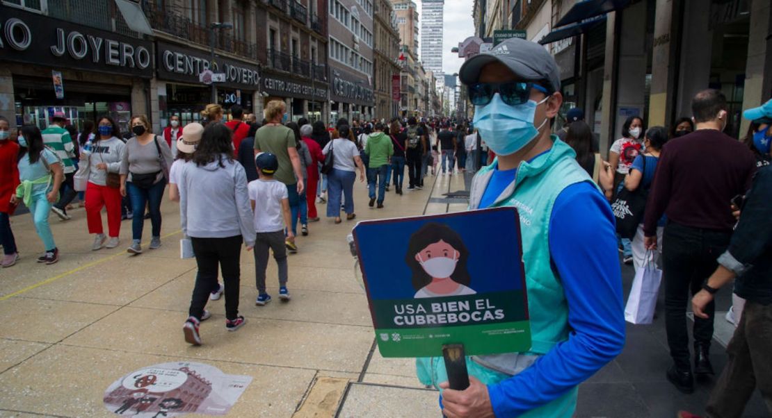 Un empleado de la Secretaría de Gobernación sostiene un cartel que dice "Use la máscara facial correctamente" en el centro histórico de la Ciudad de México el 16 de octubre de 2021, un día después de que la alcaldía de la capital mexicana anunciara que reducirá las restricciones establecidas para combatir el nuevo coronavirus a la COVID-19.