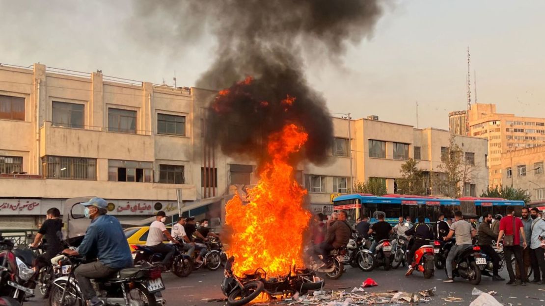 La gente se reúne junto a una motocicleta en llamas en la capital iraní, Teherán, el 8 de octubre de 2022.