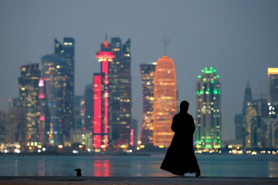 Una mujer de pie junto al mar con vistas al horizonte de torres de la capital de Qatar, Doha, el 13 de diciembre de 2021.