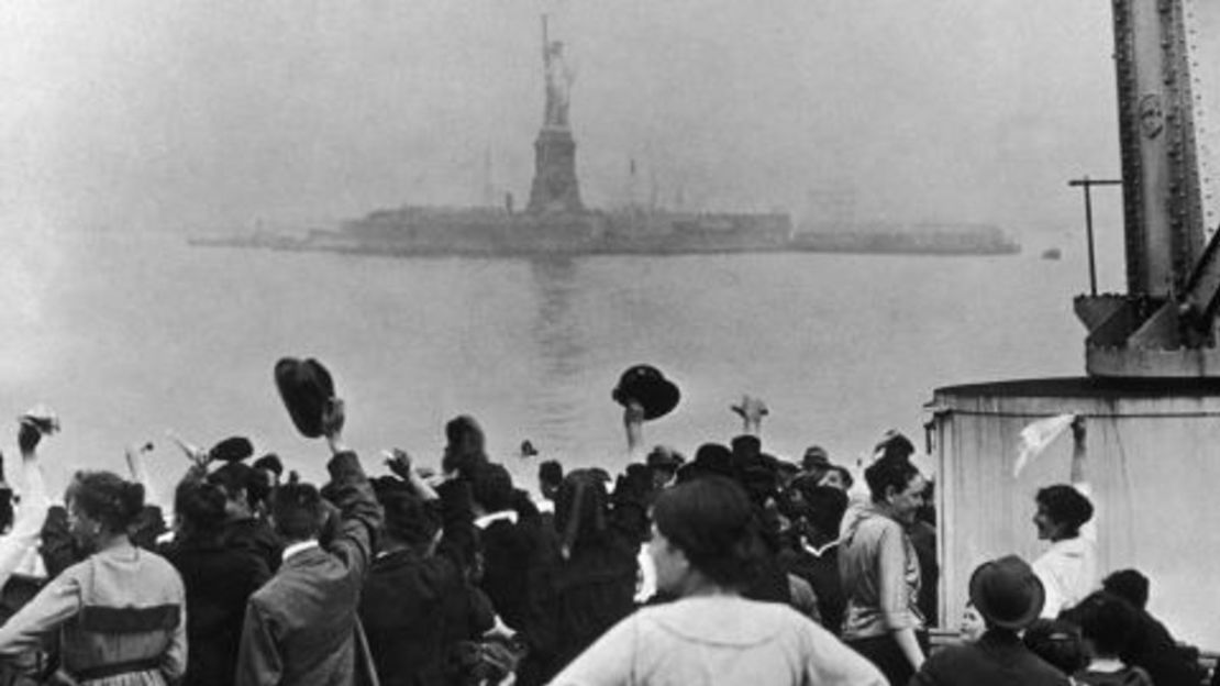 En esta foto de archivo de principios del siglo XX, un grupo de inmigrantes celebra al ver por primera vez la Estatua de la Libertad y la Isla Ellis en el puerto de Nueva York.