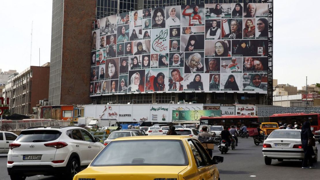 Los iraníes pasan frente a una enorme cartelera que muestra un montaje de imágenes tituladas "Las mujeres de mi tierra", con mujeres iraníes que observan el uso del hiyab, en la plaza Valiasr en Teherán, el 13 de octubre.