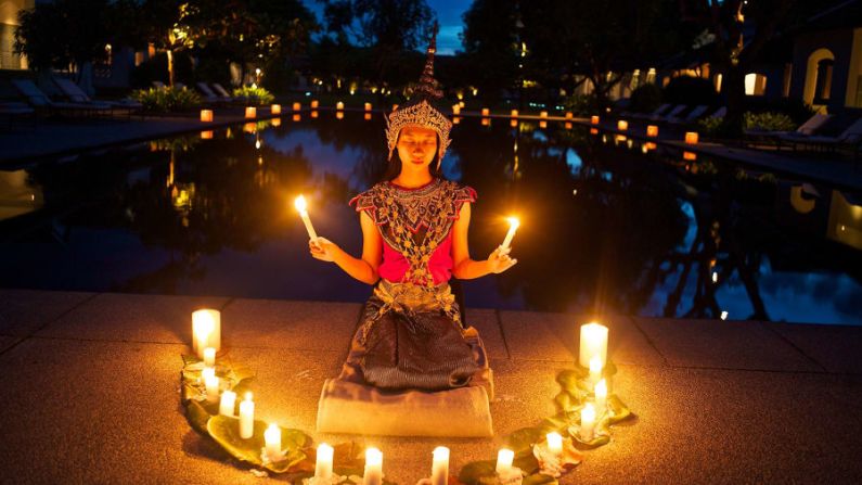 Laos: unas velas rodean a una joven bailarina de nang keo en Luang Prabang, la antigua capital imperial de Laos a la que ahora se puede llegar en tren bala. El tren está haciendo que Laos sea más accesible para los turistas y está brindando oportunidades económicas a la población local. Crédito: Kike Calvo/Colección de imágenes de Nat Geo