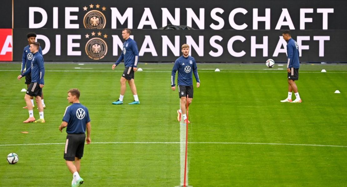 El delantero alemán Timo Werner (2D) y otros jugadores pasan junto a una pancarta con las letras 'Die Crew' (El equipo) mientras se calientan durante una sesión de entrenamiento del equipo nacional de fútbol de Alemania el 7 de octubre de 2021 en Hamburgo, norte de Alemania, antes el partido de fútbol de clasificación del equipo para la Copa Mundial de la FIFA 2022 del Grupo J contra Rumania el 8 de octubre.