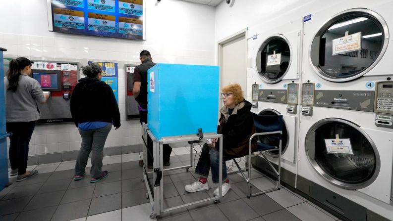 Jeanette Buchanan emite su voto electrónico mientras los clientes de Su Nueva Lavanderia colocan efectivo en tarjetas de lavandería cerca del Aeropuerto Midway de Chicago este martes.