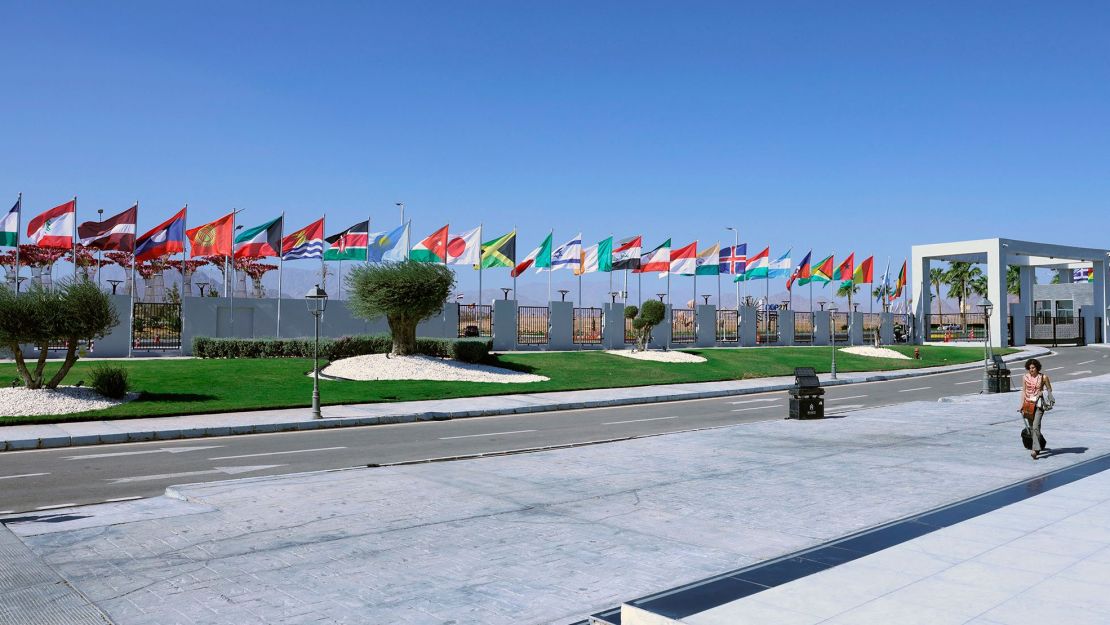 Una mujer pasa frente a las banderas de los países que participan en la cumbre climática COP27 en el centro turístico de Sharm el-Sheikh, en el mar Rojo, el 12 de noviembre de 2022. Crédito: AHMAD GHARABLI/AFP a través de Getty Images