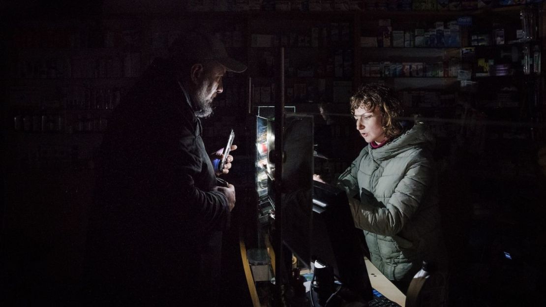 En una farmacia de Lviv, un hombre utiliza la luz de su teléfono para ayudar al farmacéutico a encontrar productos, en medio de los apagones, el 16 de noviembre. Crédito: Gaelle Girbes/Getty Images