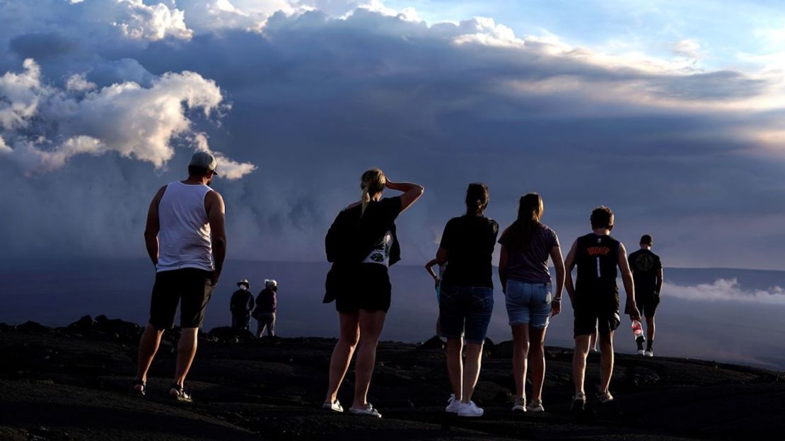 Un grupo de personas se para sobre la roca de lava de una erupción anterior cerca del volcán Mauna Loa, mientras entra en erupción el miércoles, cerca de Hilo, Hawai.